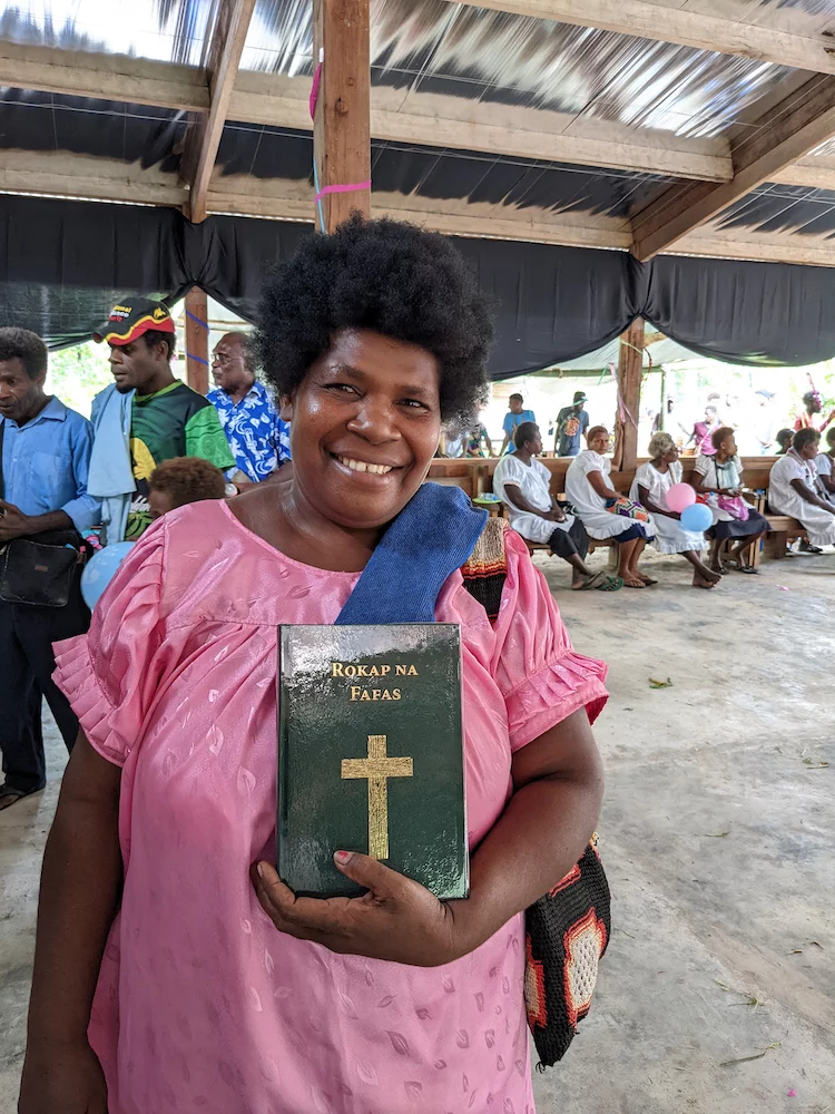 Image of a woman holding her copy of the Fanamaket New Testament, at the launch event in Papua New Guinea in November 2021