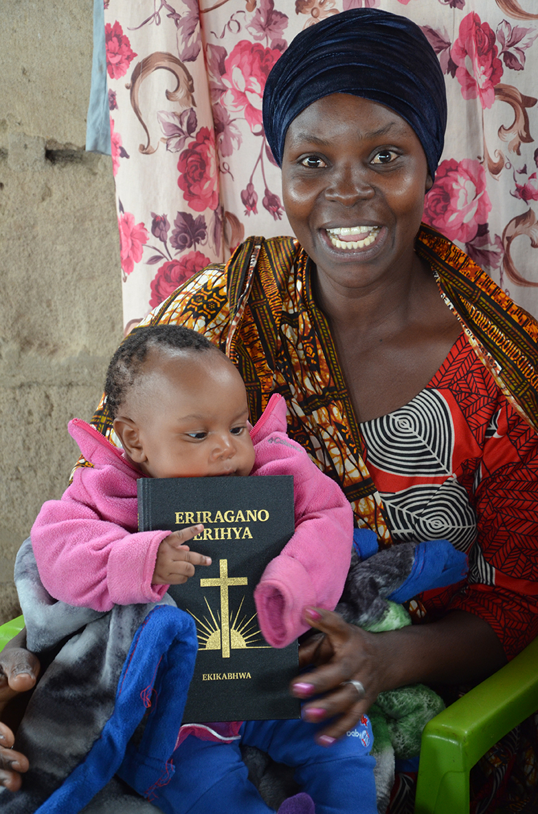 Image of a young mother getting excited about having a copy of the Kabwa New Testament to share with her family.