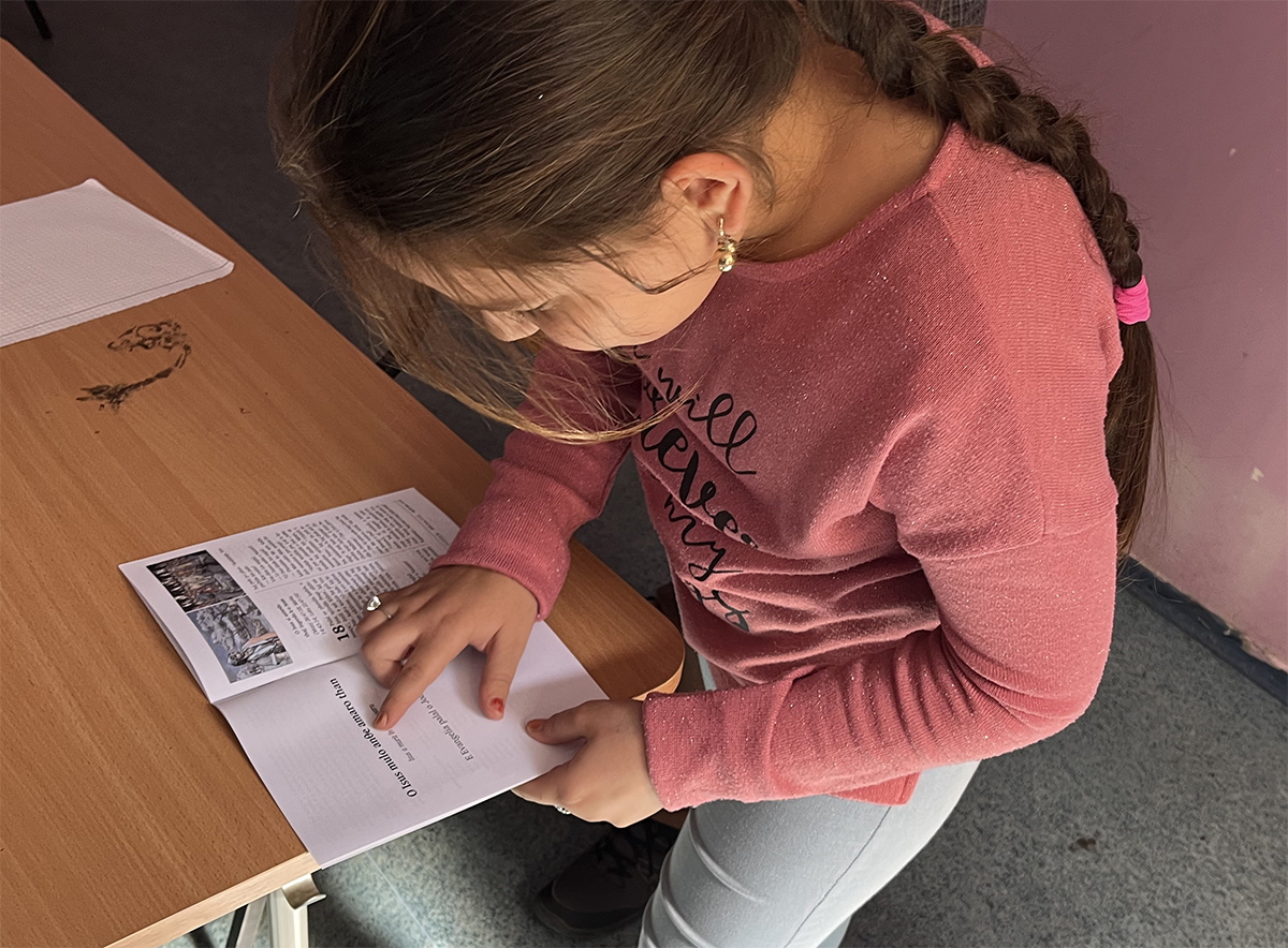 Image of a Roma girl reading the Standard Romani translation of John in her school classroom