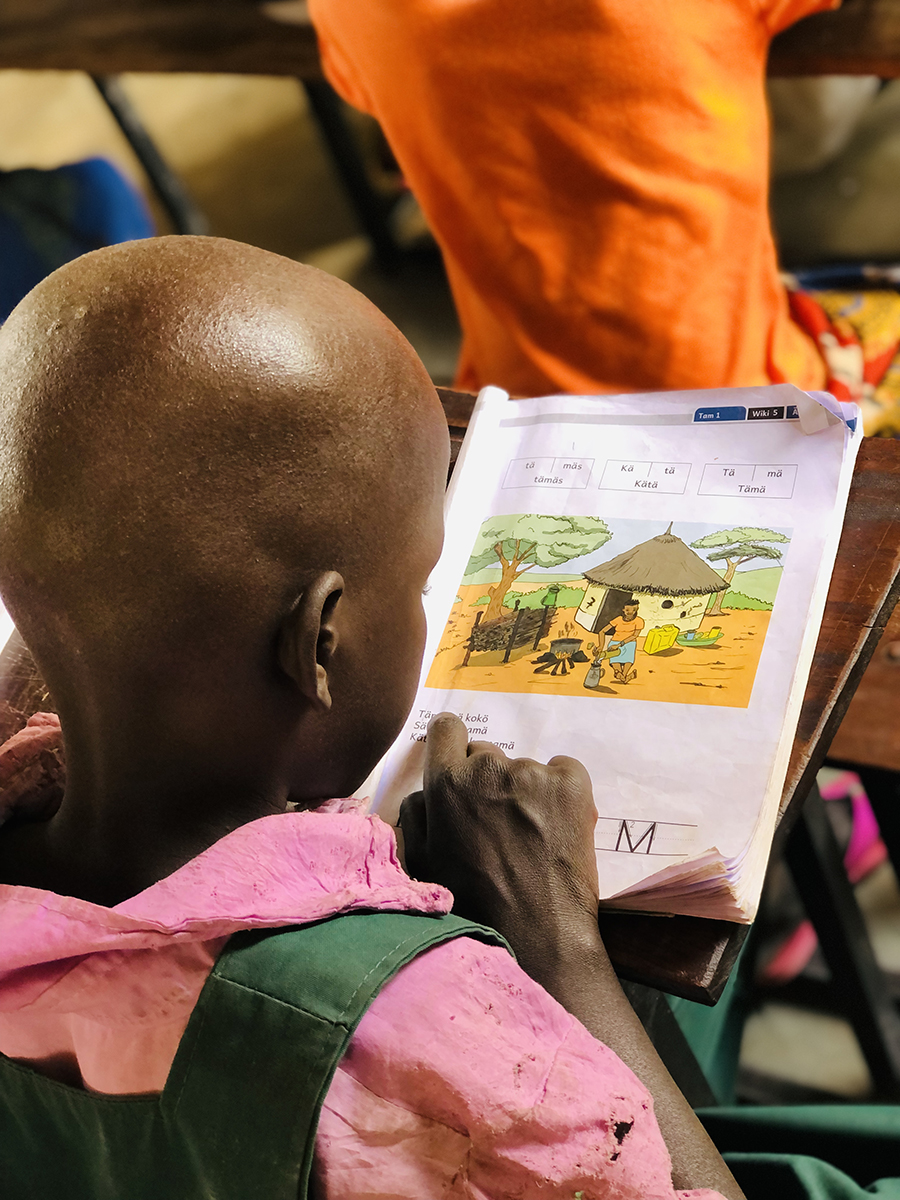 Image of a Pokot child reading in their book during a school class