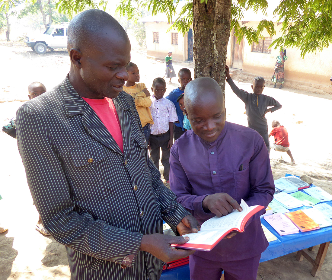 Image of two men looking at the Safwa New Testament at its launch event