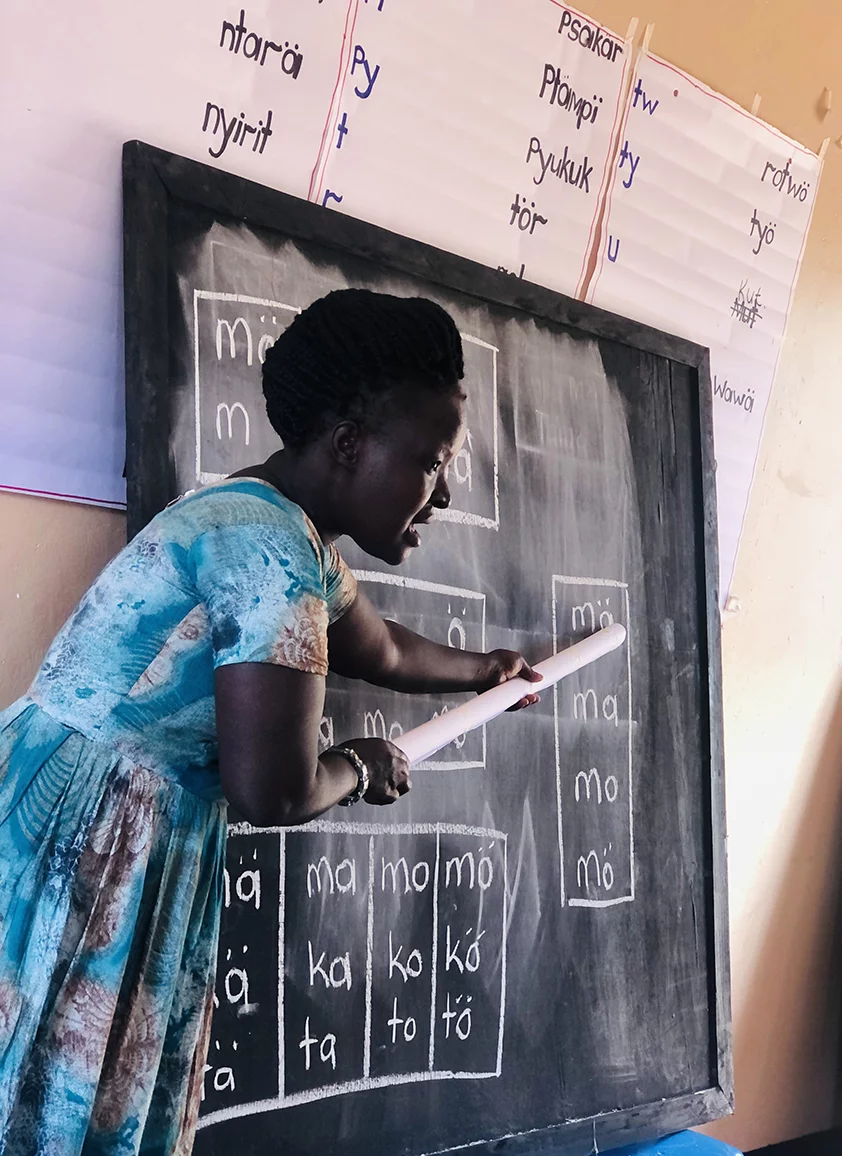 Image of a Pokot primary school teacher pointing out Pokot words on a chalkboard