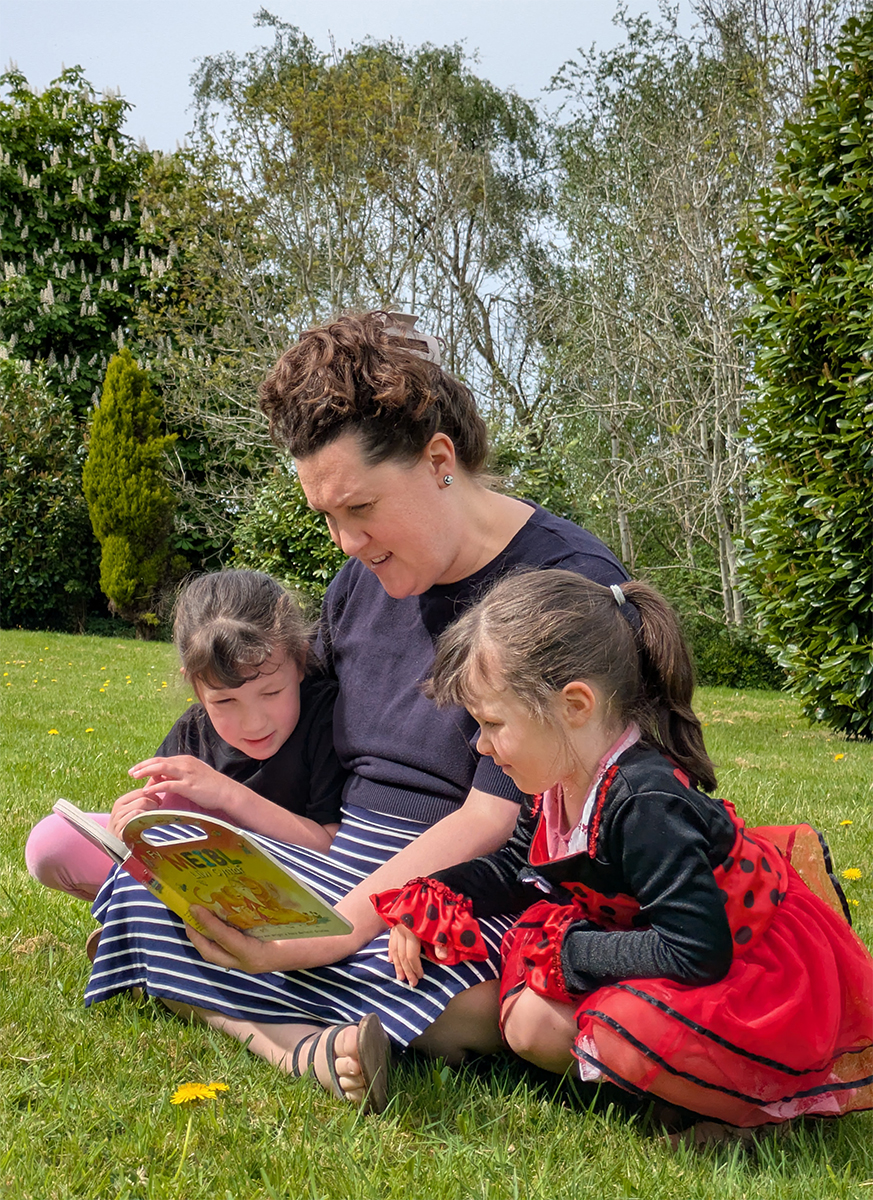 Image of Lowri Turner reading a Welsh-language Scripture book to her children