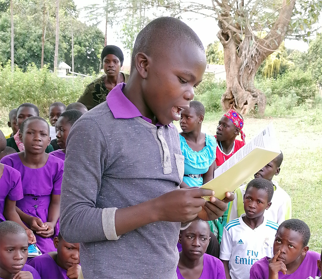 Image of a boy reading a book in his language in Uganda