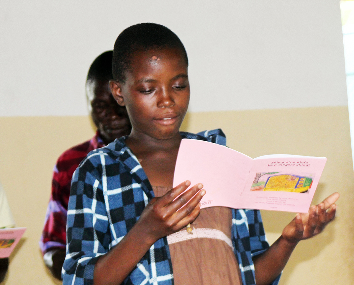 Image of a girl reading a Let's Read Together book in her language in Uganda