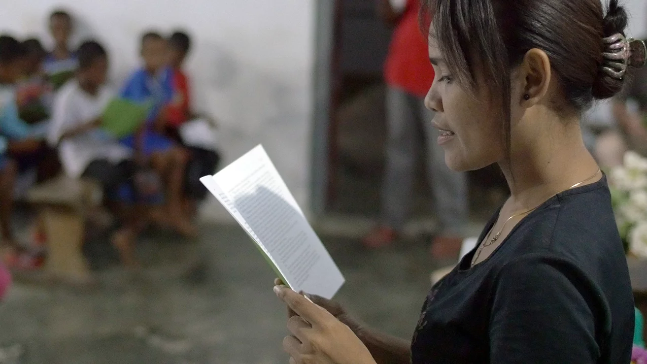 Image of Bible translator Yoke reading Dobel Scriptures in church in the Aru Islands